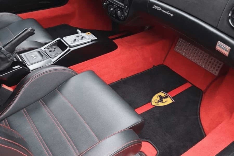 Gepflegter Ferrari-Innenraum mit roten Fußmatten
